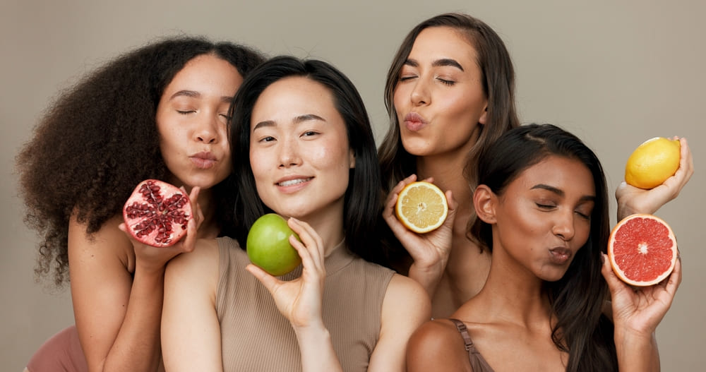 Mulheres com diferentes tons de pele segurando frutas com vitamina C para o cabelo