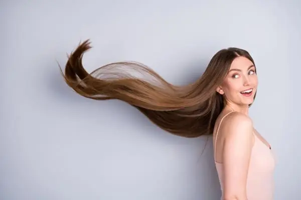 mulher branca com os cabelos ao vento estimulando o crescimento capilar de forma saudável