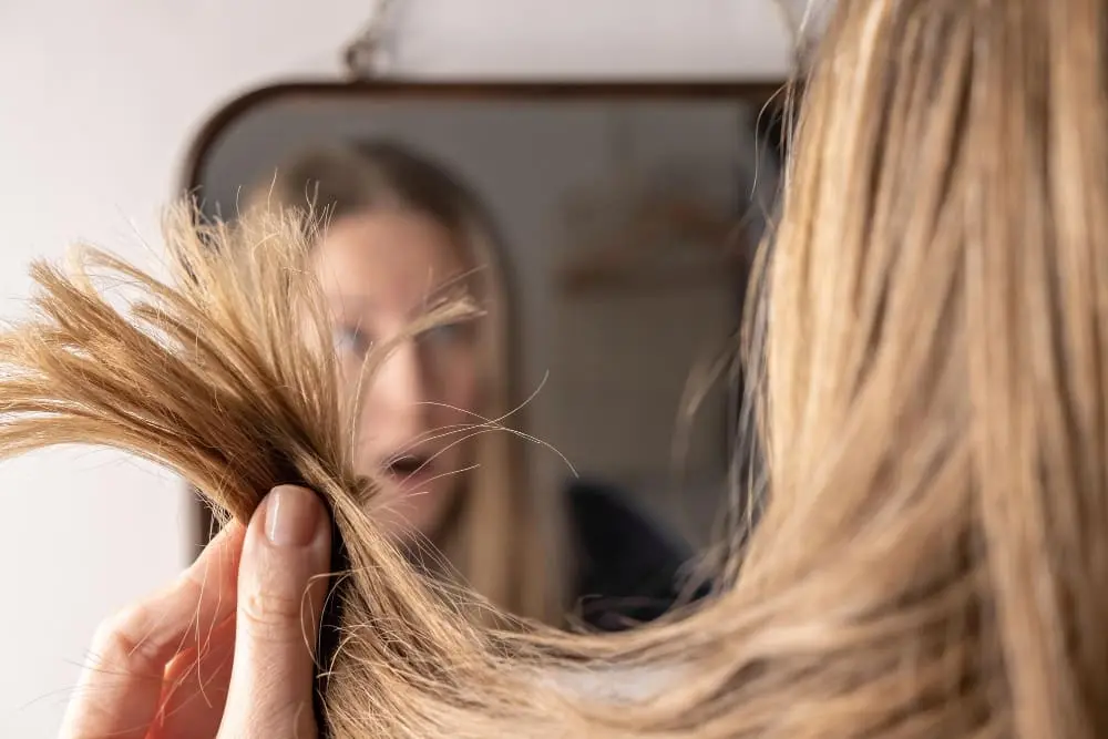 mulher-loira-em-frente-ao-espelho-frustada-com-a-saudo-do-seu-cabelo